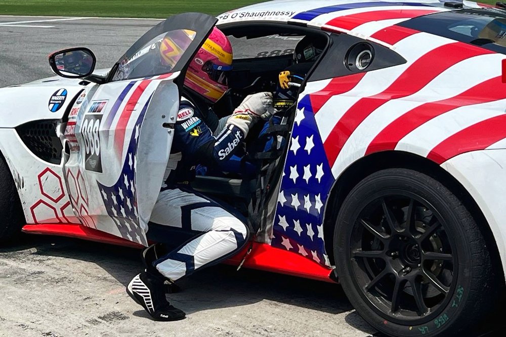 A picture of a woman adjusting the seat on a race car